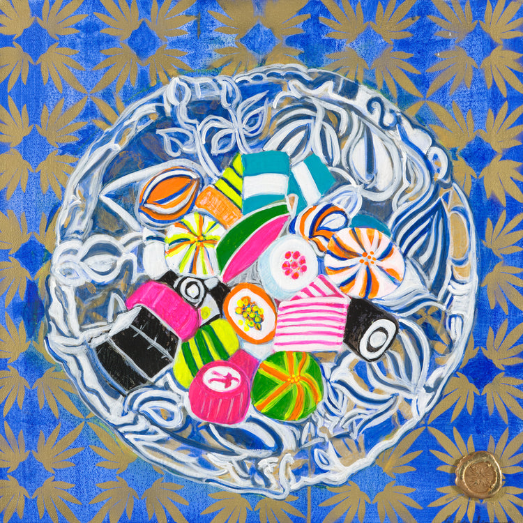 Crystal bowl with bright colored hard candies with gold four leaf design on royal blue background